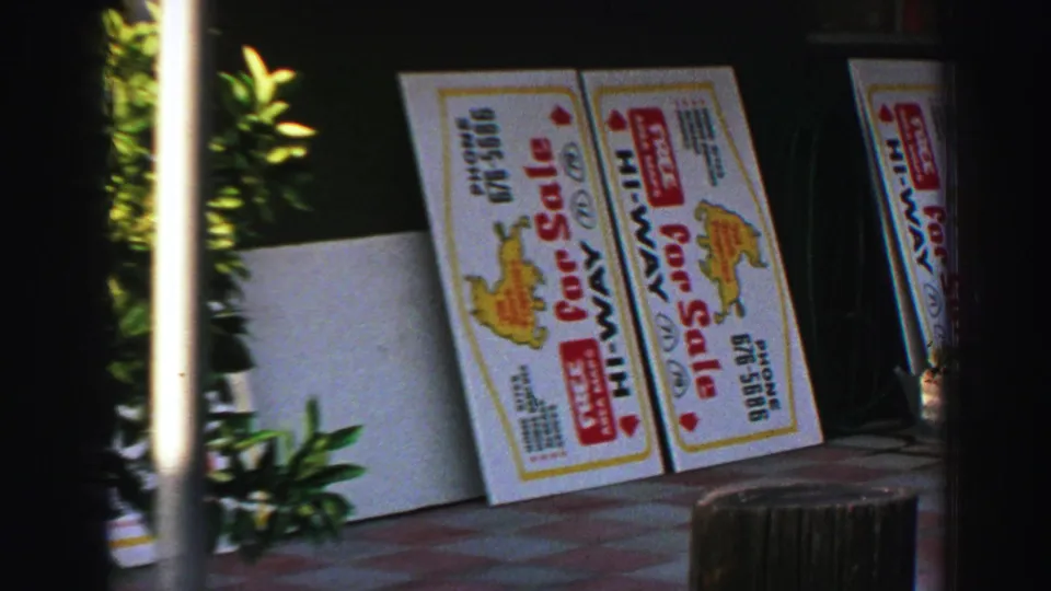 1969 Lake Tahoe sidewalk view with Hi-Way for sale signs, a small tree, and shaded storefront frontage.