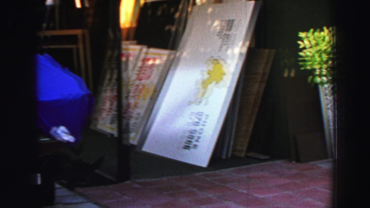 Handheld 1969 Lake Tahoe street view with a leaning signboard, boards, sidewalk tile, and dark storefront recesses.
