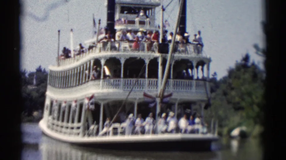 1959 Disneyland visitor footage showing a white riverboat with seated and standing passengers on open decks.