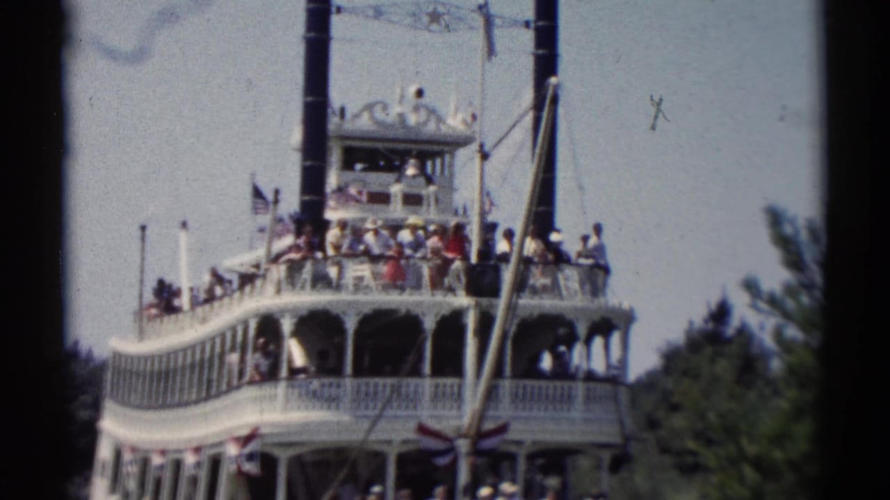 Riverboat seen from the side with passengers gathered along the railings.