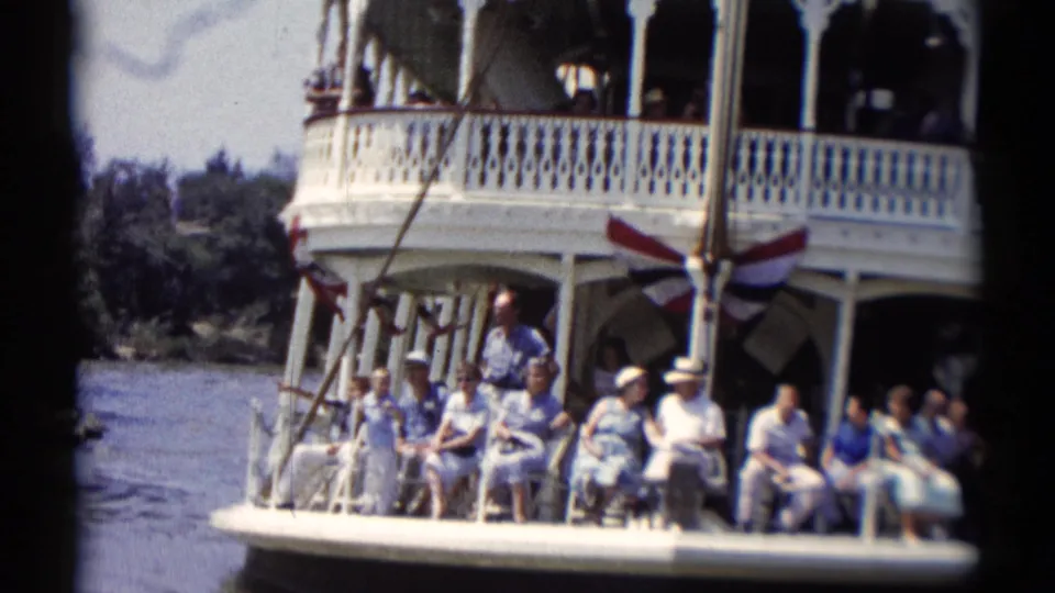 Closer 1959 Disneyland riverboat view showing seated passengers near the bow beneath white railings and bunting.