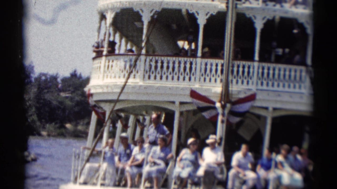 Tourists seated on the lower deck of a white riverboat with an upper balcony above.