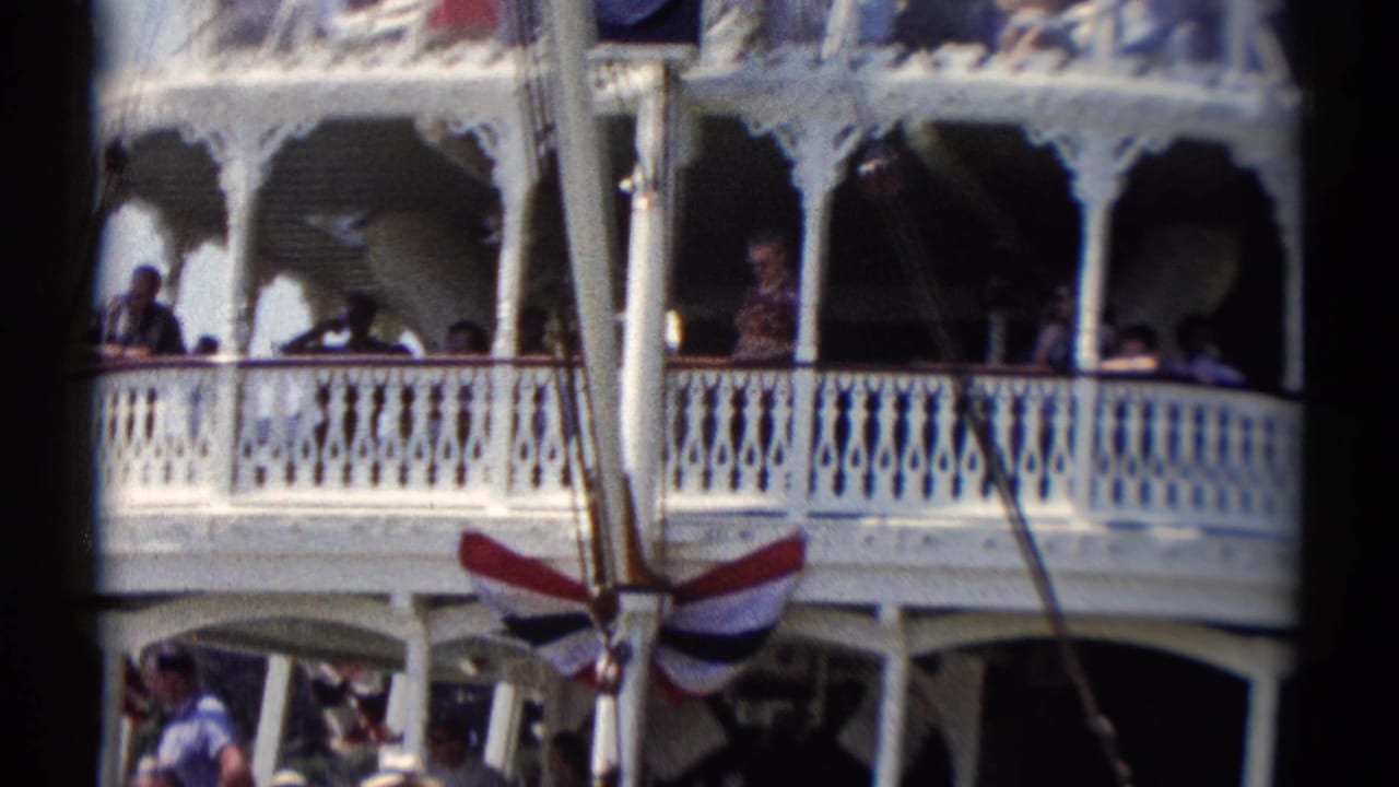 White riverboat decks with passengers behind ornate railings and striped bunting.