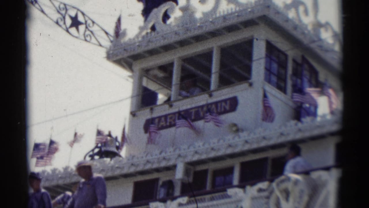 Mark Twain Riverboat upper deck with flags, passengers, windows, and ornate trim.