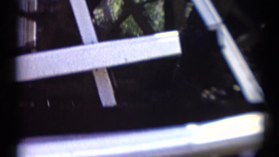 1959 Disneyland 8mm frame showing angled boat supports, white trim, dark water, and reflected light.