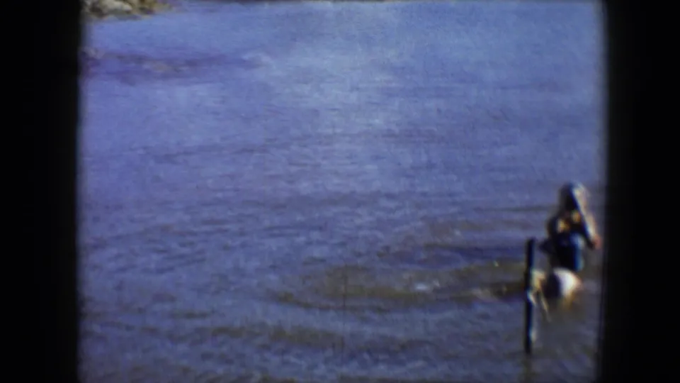 A soft 8mm frame shows swimmers partly cropped at the right edge, with rippled lake water filling most of the view.