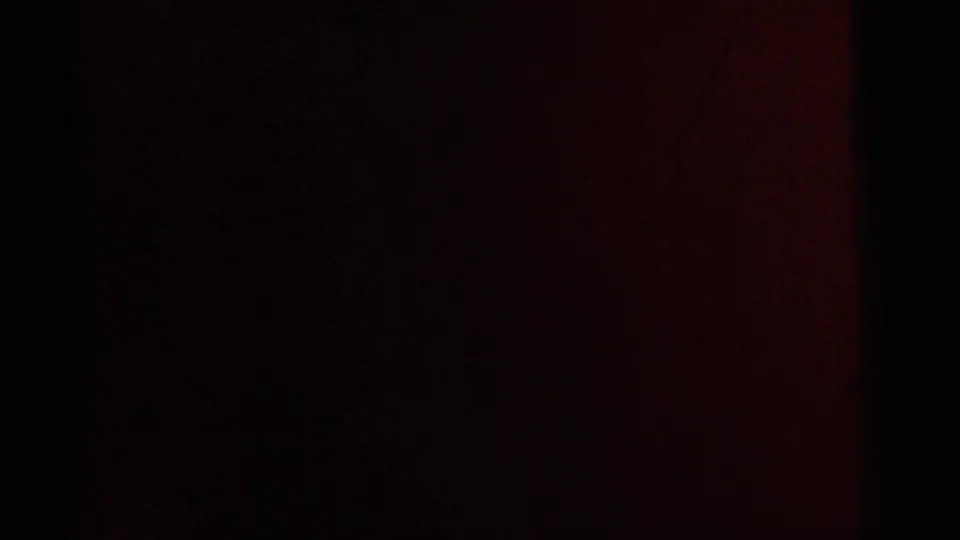 Dark 1961 8mm frame from Gary, Indiana showing a shadowed interior with a reddish vertical band and minimal visible detail.