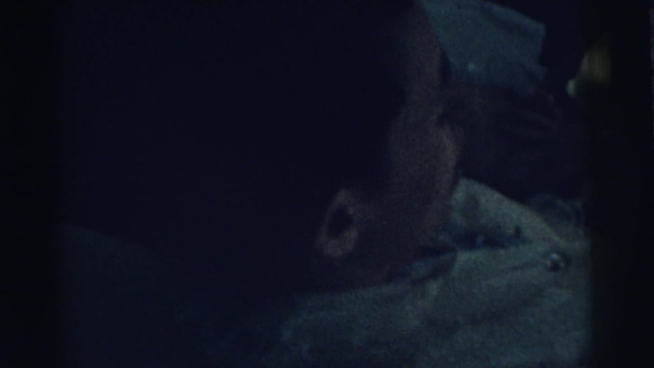 Dark frame with the infant's face partly visible in profile.