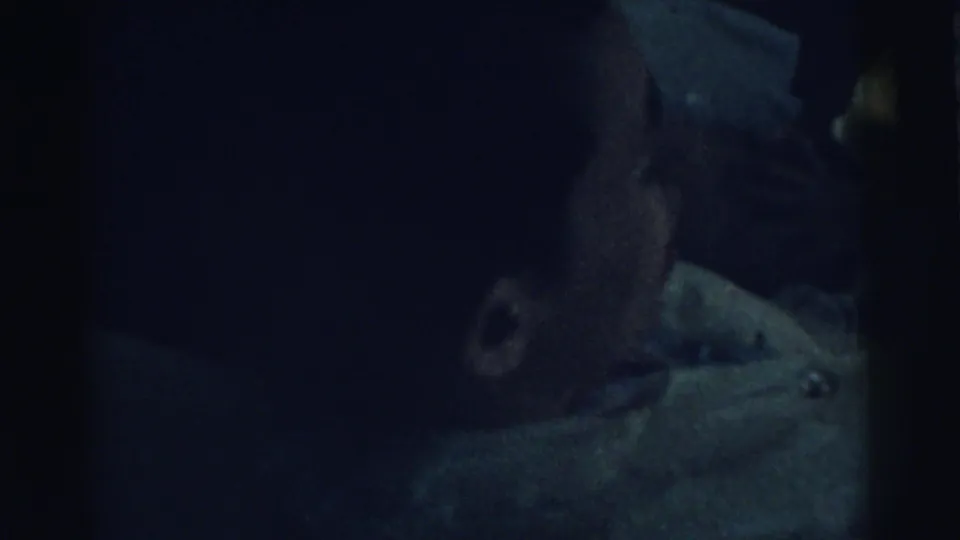 Low-light 8mm view of the infant's face partly in shadow during the bottle-feeding scene in Gary, Indiana, 1961.