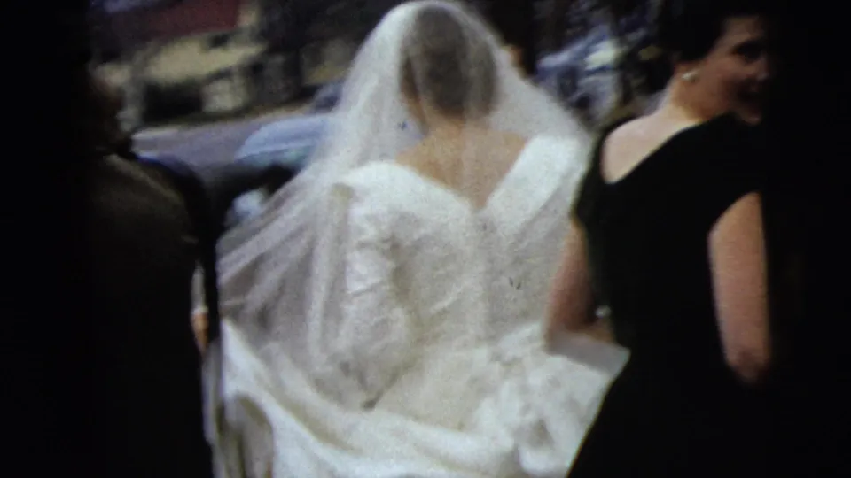 The bride's veil and gown fill the frame as attendants walk beside her on a Moline street in the supplied 1962 context.