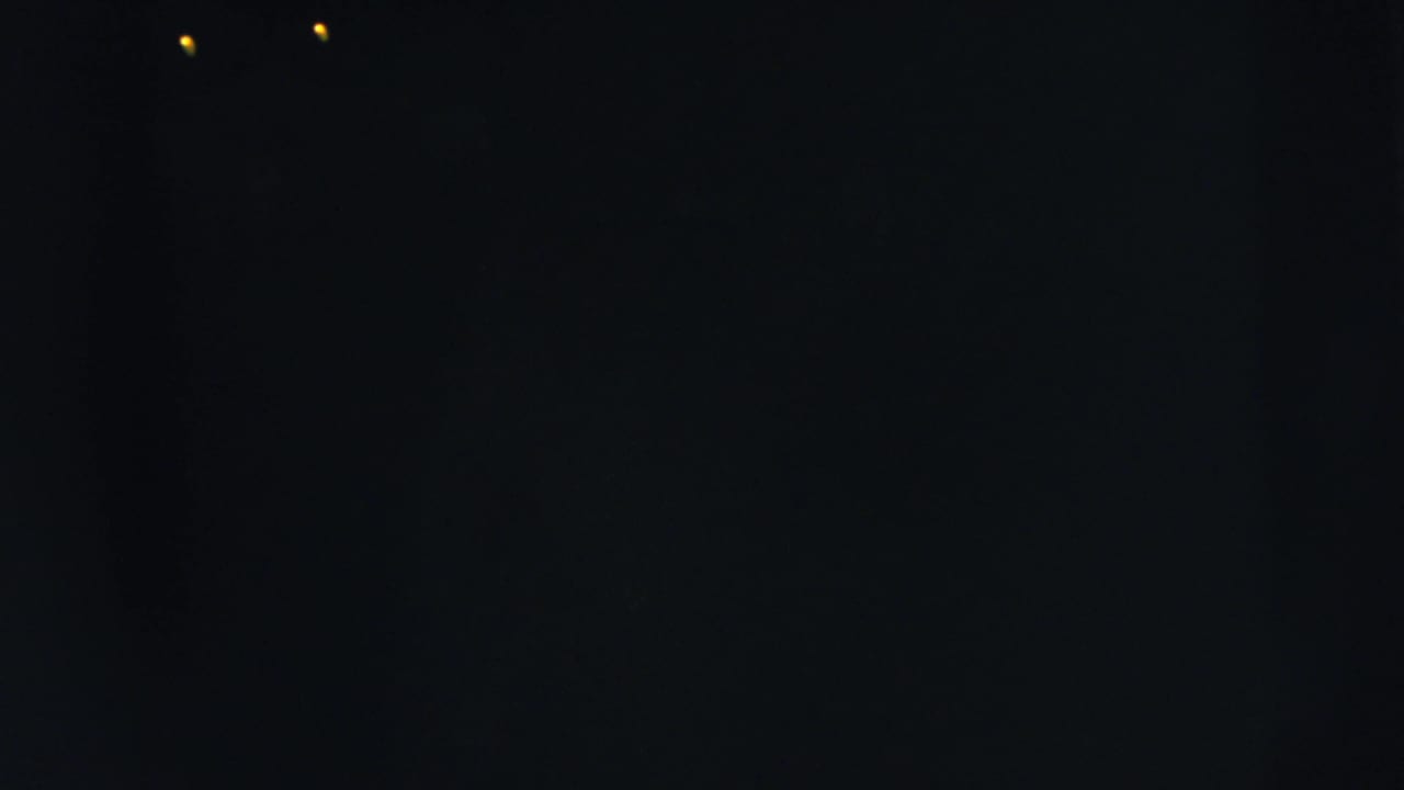 Nearly black frame with two small yellow light points near the top.