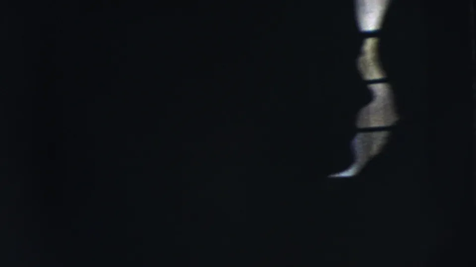 Dark 1962 Moline frame showing a narrow section of barred window light with human forms mostly obscured.