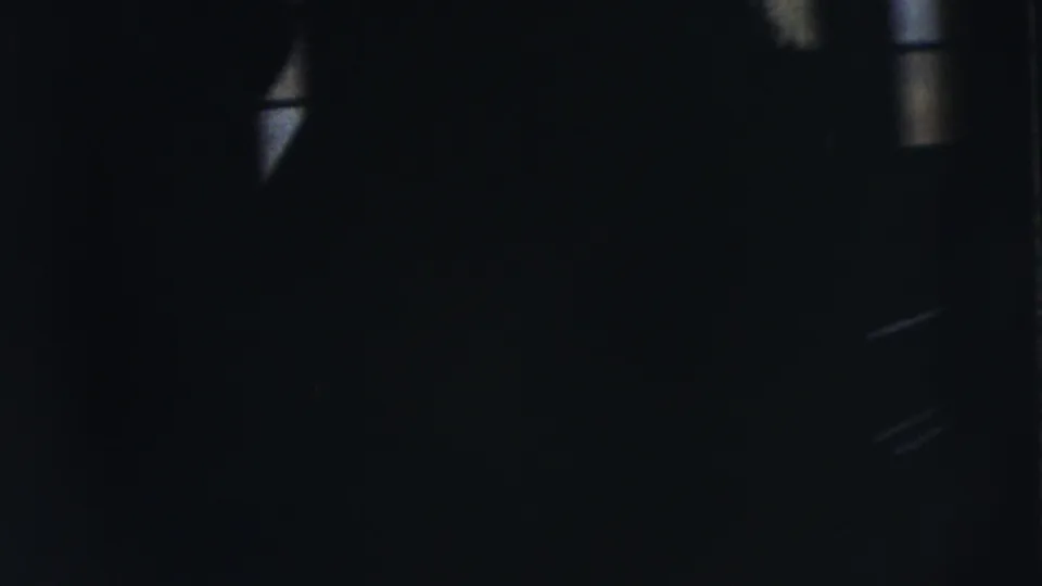 In Moline, Illinois wedding footage from 1962, the bride and groom are partly visible near a shadowed doorway as the frame is mostly dark.