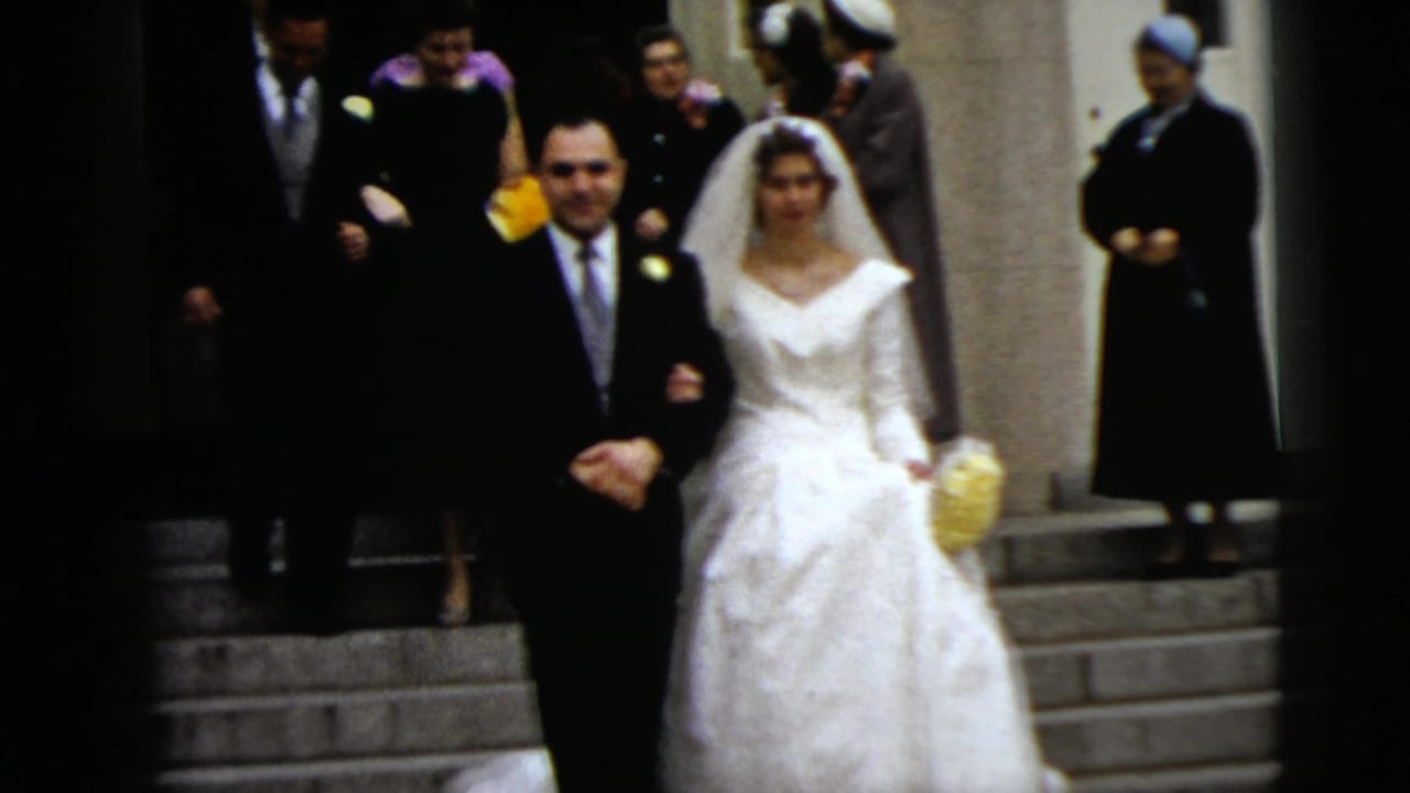 Newly married couple descends church steps while guests stand in the doorway.