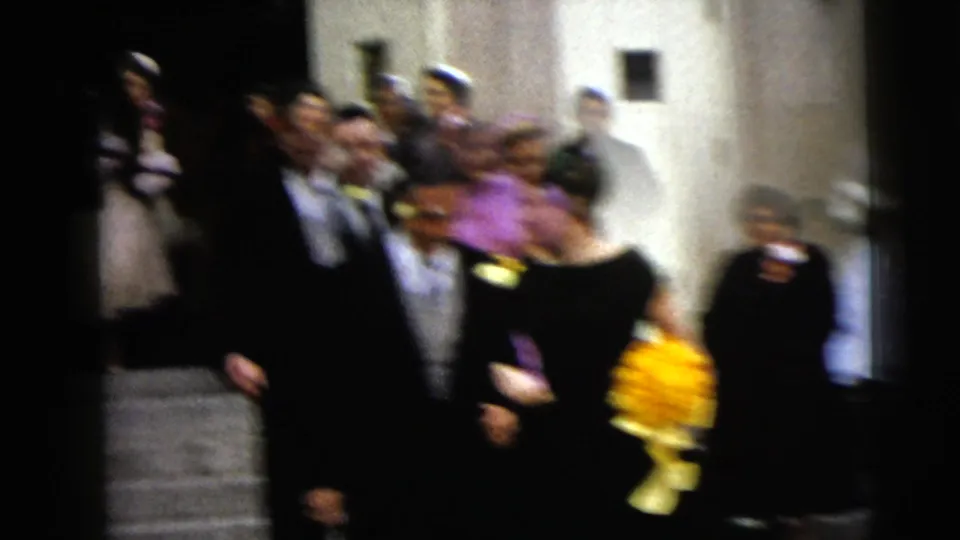 A handheld, blurred frame shows the wedding party and guests descending stone steps after the church ceremony.