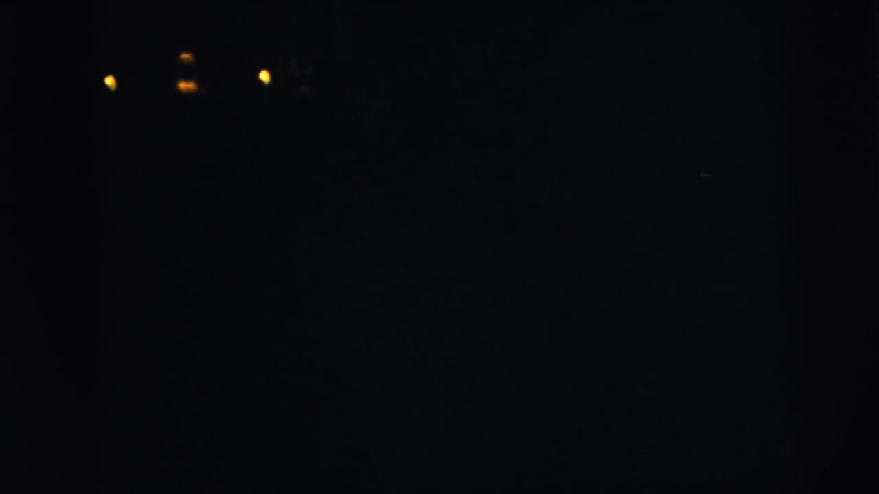 Dark underexposed view with small lights and the wedding party partly visible at the church entrance.