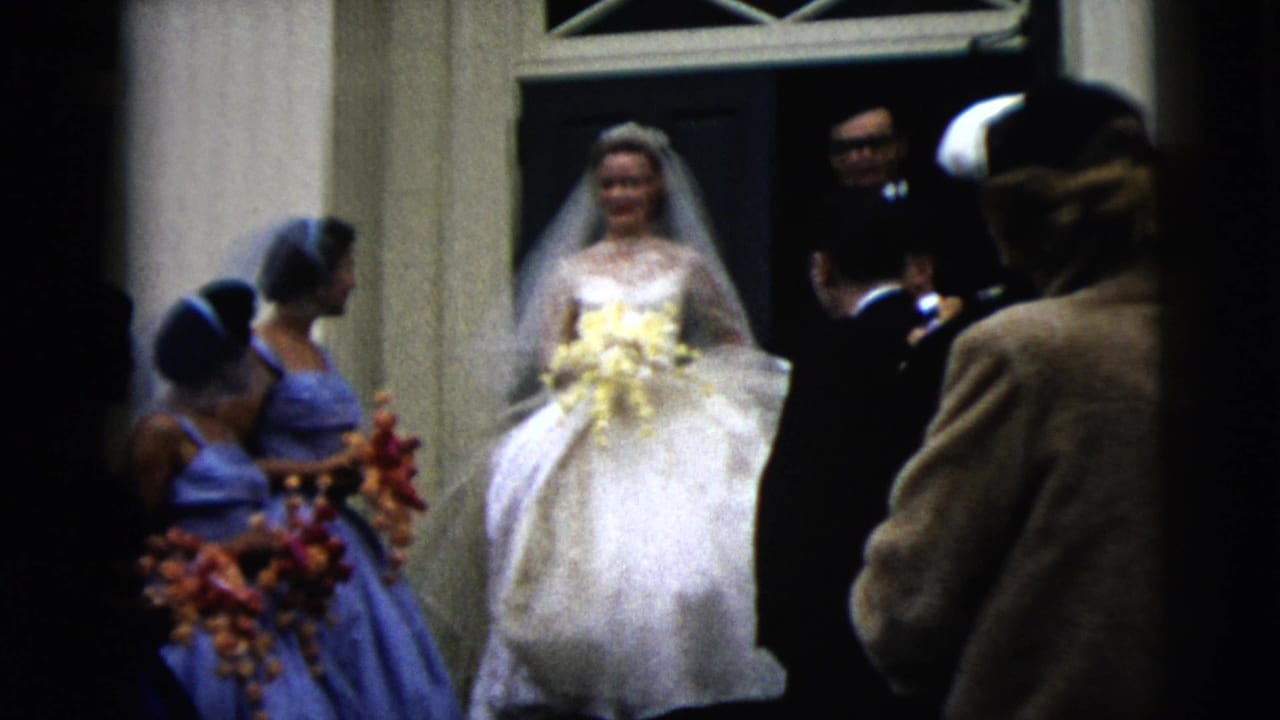 Bride in a white gown stands at a church doorway beside bridesmaids and guests.