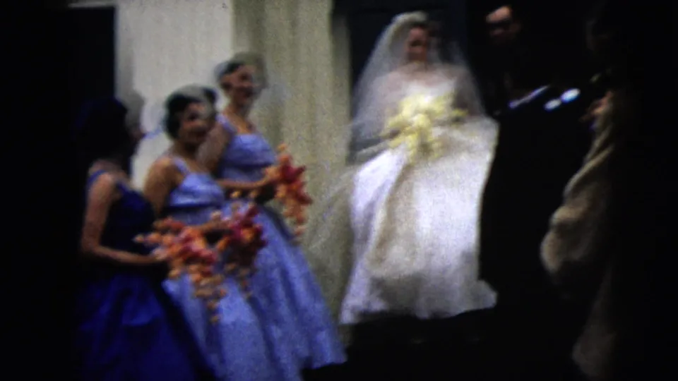 Bridesmaids in blue dresses hold floral arrangements beside the bride on church steps in 1962 Moline wedding footage.