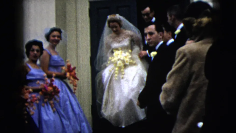 The bride moves out from the doorway while bridesmaids in blue dresses and suited men stand close by in the Moline wedding scene.