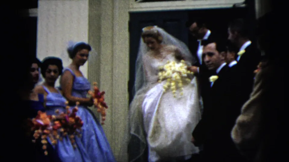 1962 Moline, Illinois wedding party outside a building, with the bride in a veil beside bridesmaids carrying bright bouquets.