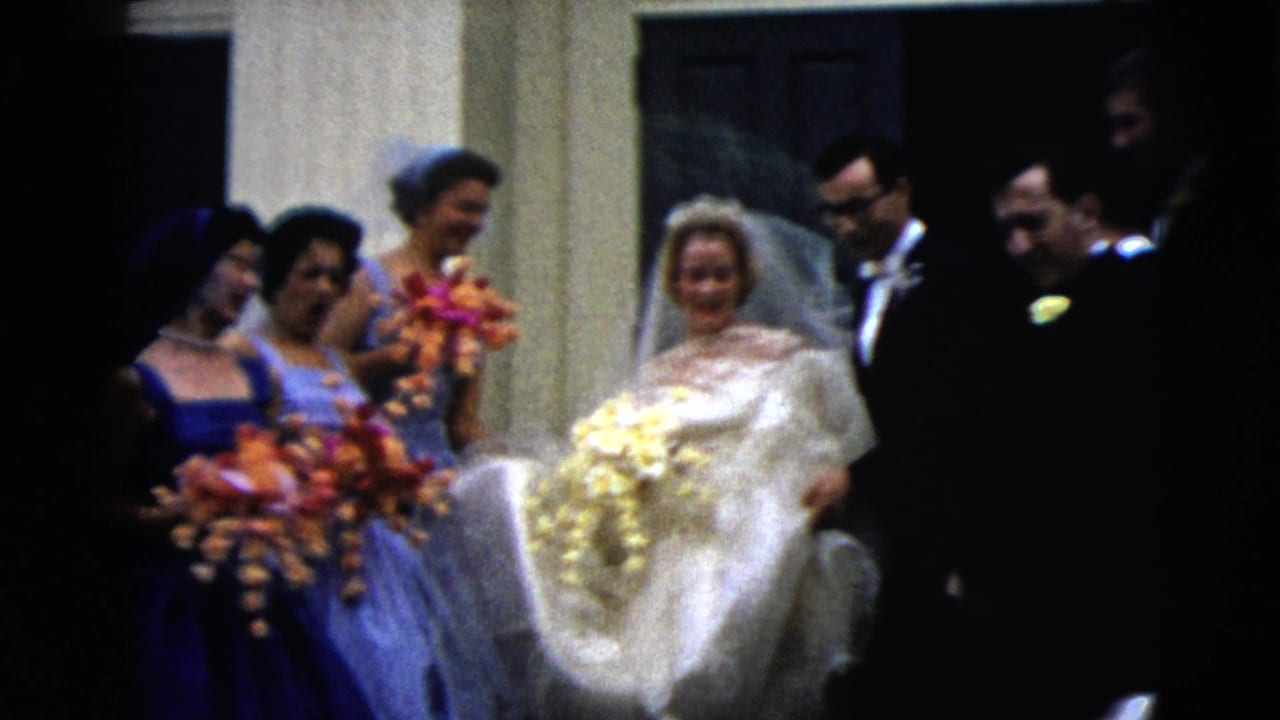 Bride with veil and bouquet stands with bridesmaids and men in tuxedos near a doorway.