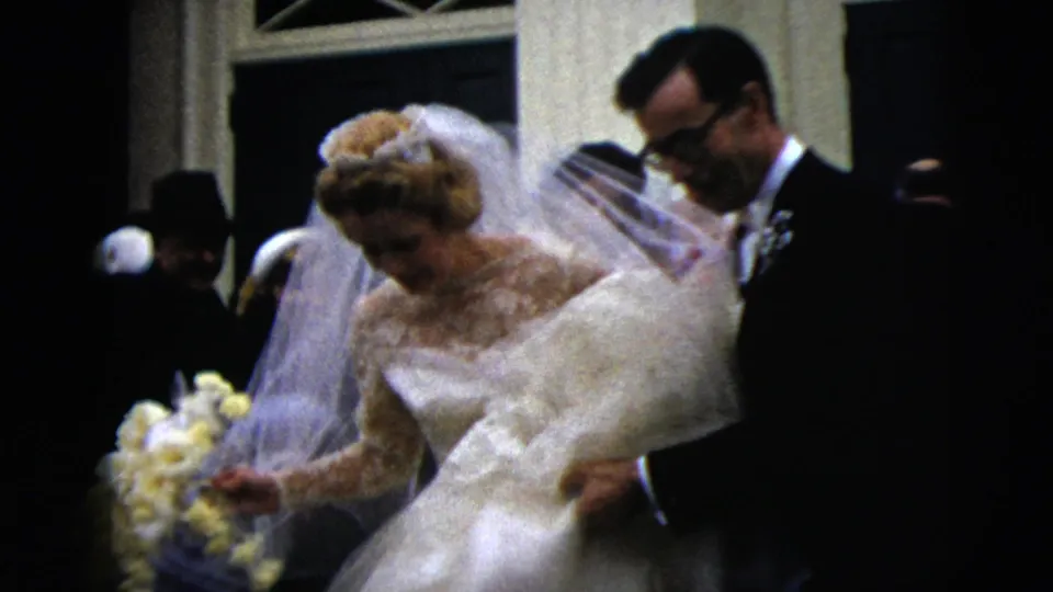 At a Moline, Illinois wedding, the groom appears to help the bride manage her full lace dress while they descend the stairs.