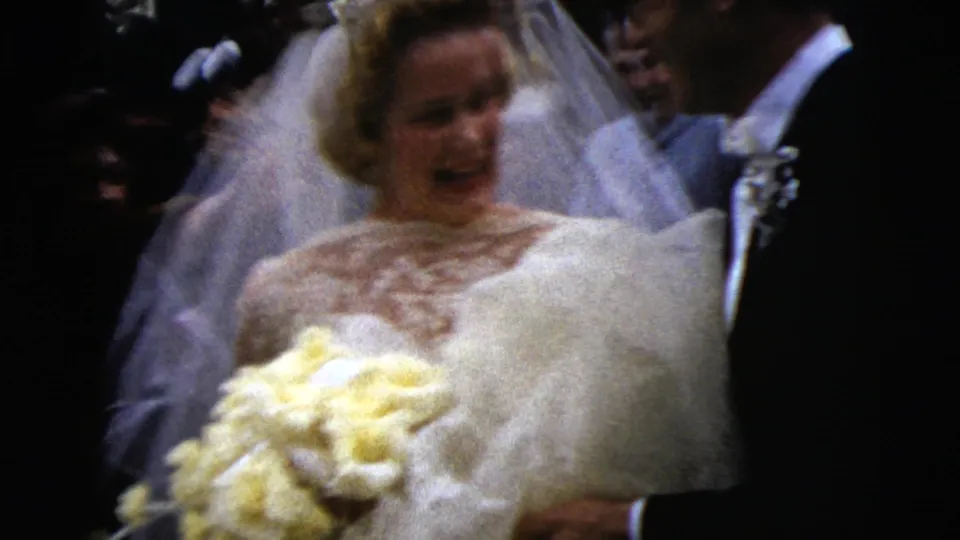 The bride faces forward with her yellow bouquet as the groom and guests stand close in the 1962 Moline wedding scene.