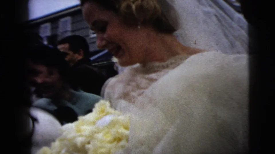 The bride smiles broadly while carrying a yellow bouquet, with her veil and lace dress visible in the 1962 Moline wedding footage.