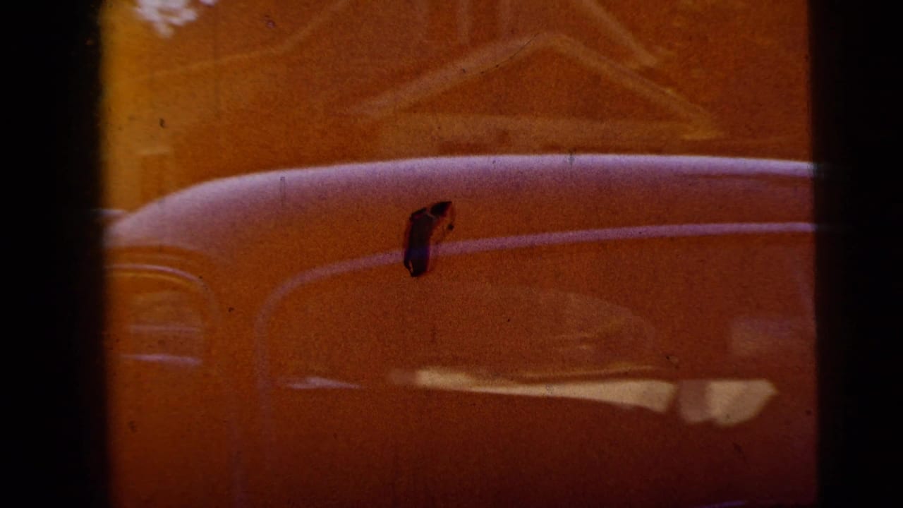 Rounded classic car roof and window seen through dark vertical foreground bars.