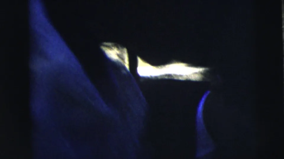 Underexposed 1962 8mm frame from the Moline home movie showing partial dark silhouettes and bright patches at the edge of the scene.