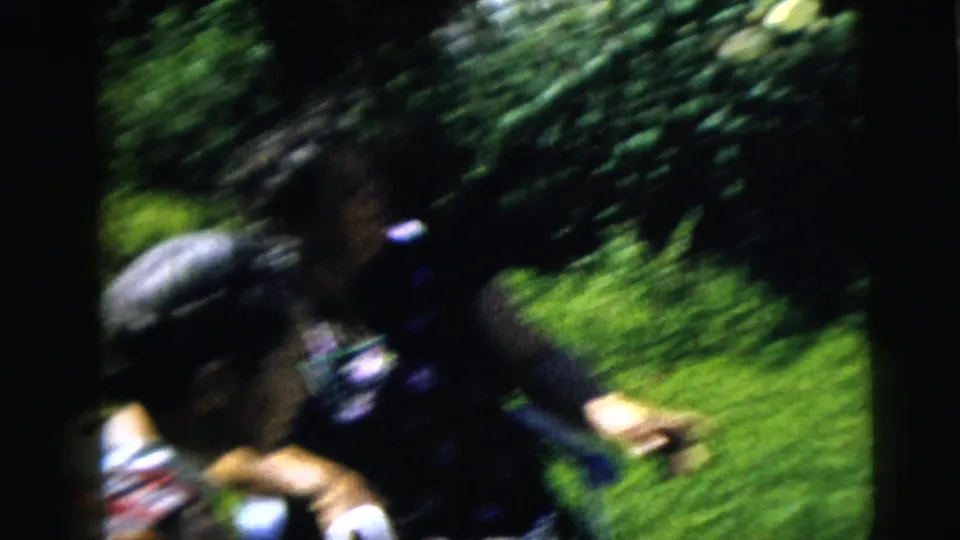 Motion-blurred 1962 8mm frame of two women moving and talking in a sunny Moline garden setting.