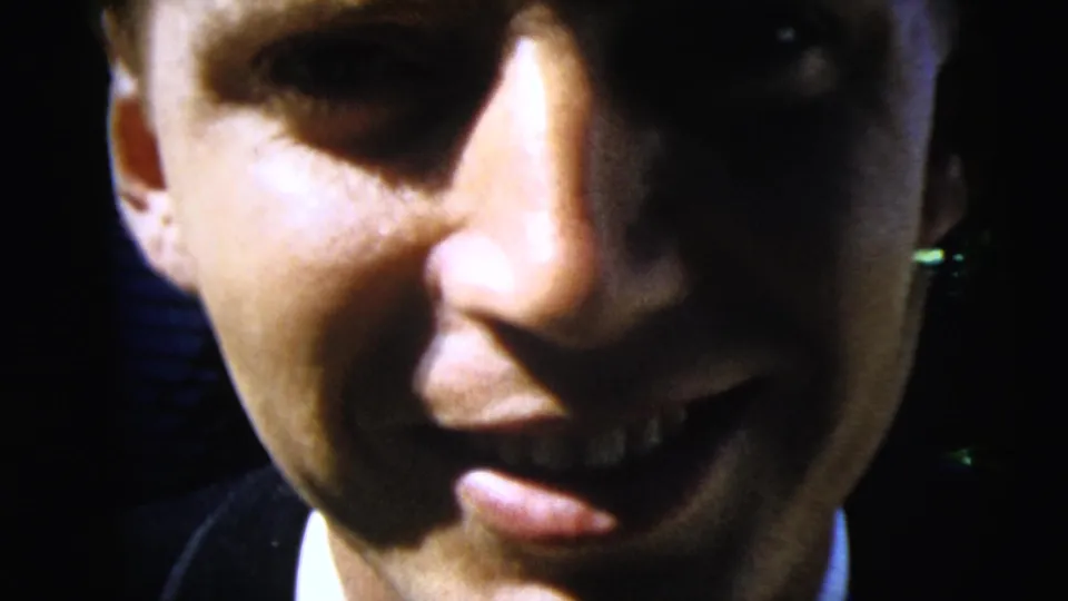 An extreme close-up frames the smiling man's face at the end of the 1962 Moline 8mm home movie, with suit collar and foliage partly visible.