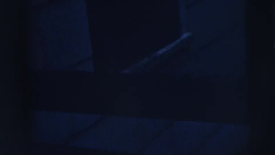 Dark 1962 home-movie frame from Moline showing indistinct interior geometry, including angled light lines and blocky wall or window shapes.