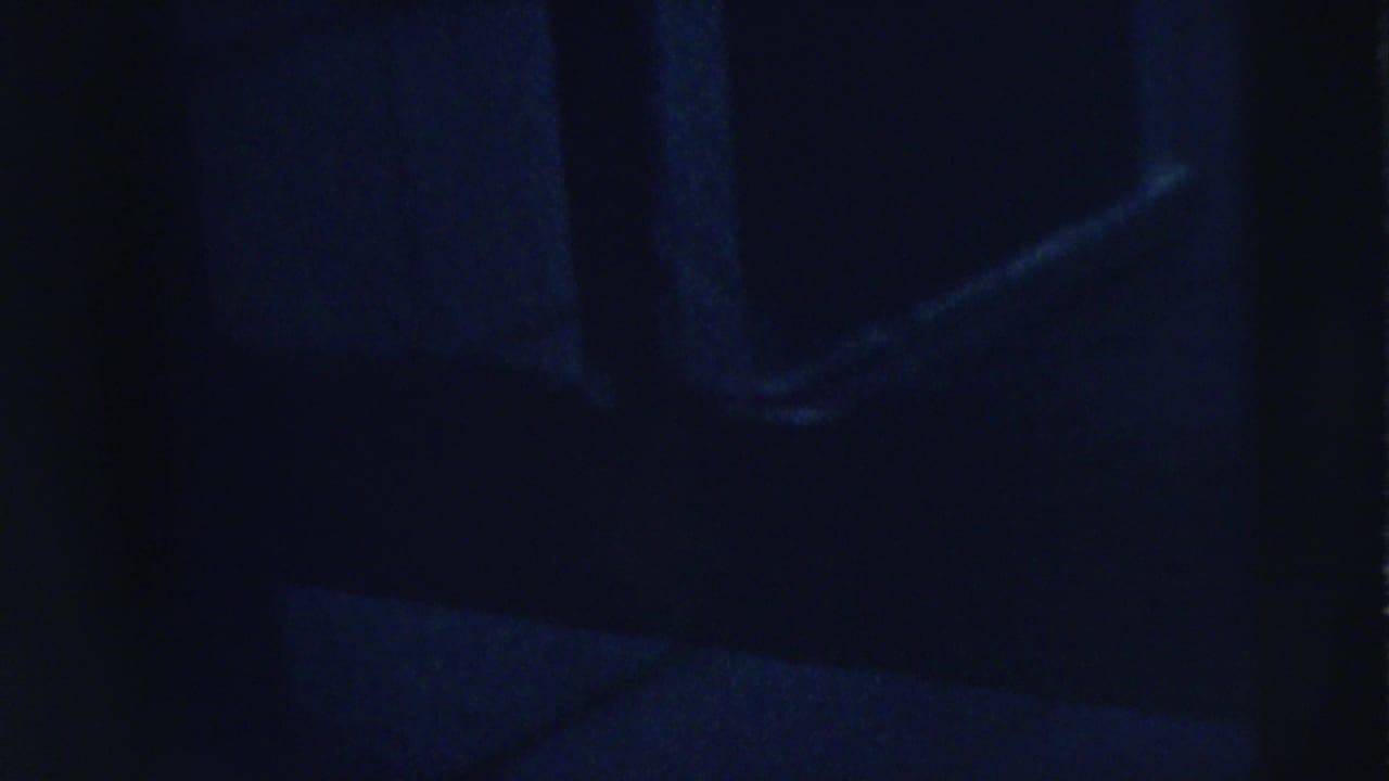Dark doorway area with faint blue-lit shapes and little visible detail.