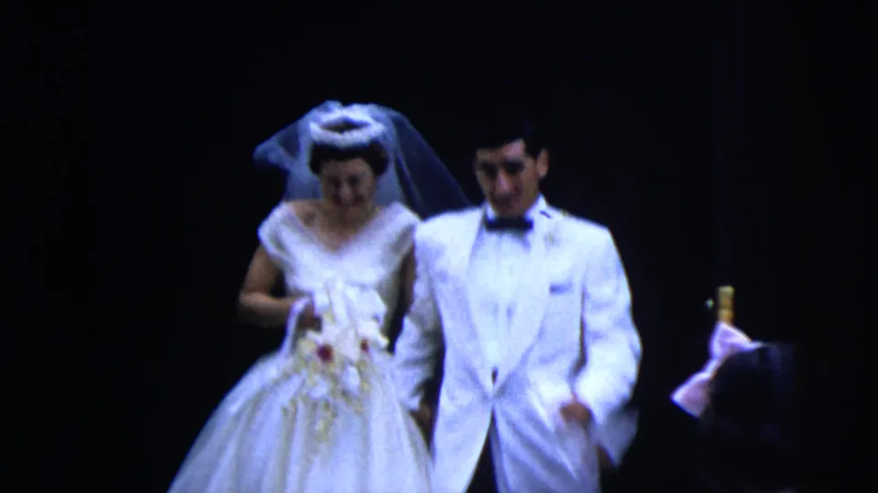 In the 1962 Moline wedding footage, the bride in a white gown and veil walks beside the groom in a white jacket.