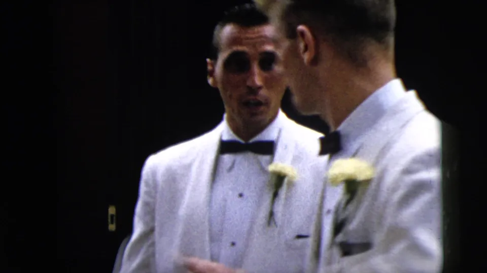 1962 Moline frame of men in white dinner jackets with boutonniere flowers conversing during a formal arrival.