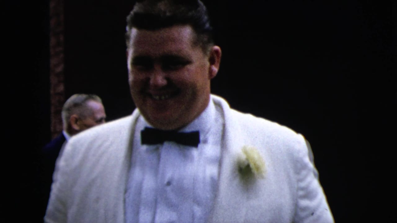 A smiling man in a white tuxedo and black bow tie stands close to the camera during a 1962 Moline formal event.
