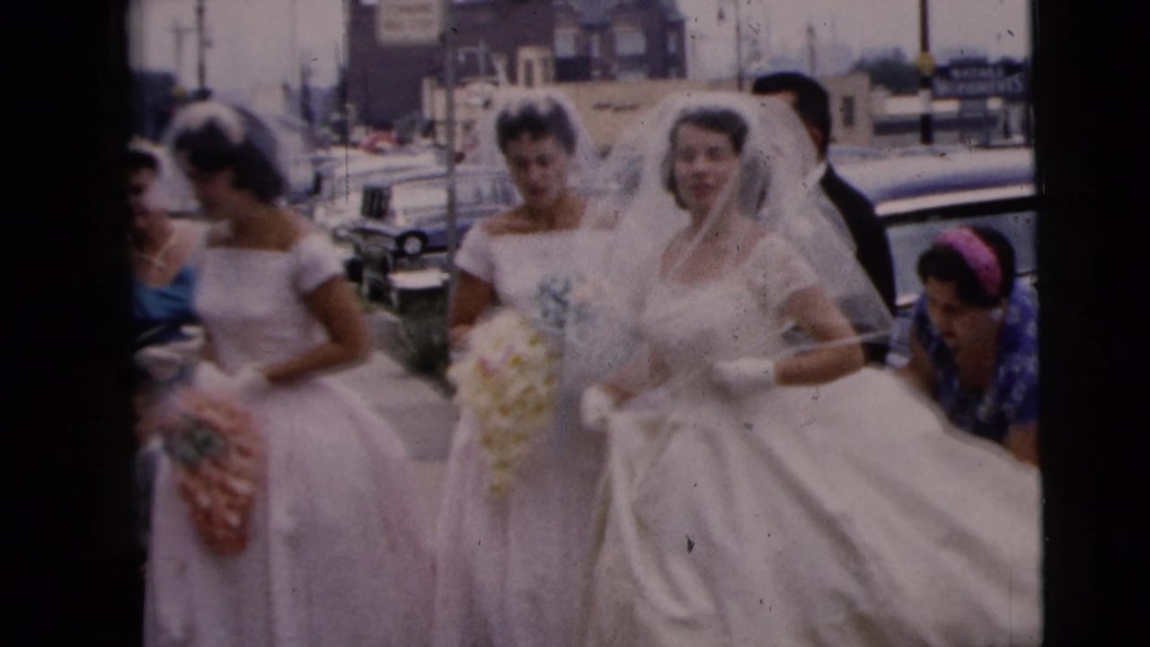 Bride and bridesmaids walk near a street with bouquets and veils visible.