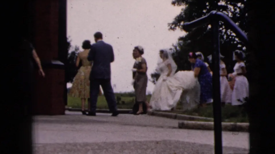 Bride and attendants stand outside a building entrance in Moline, Illinois, with the train of the gown visible.