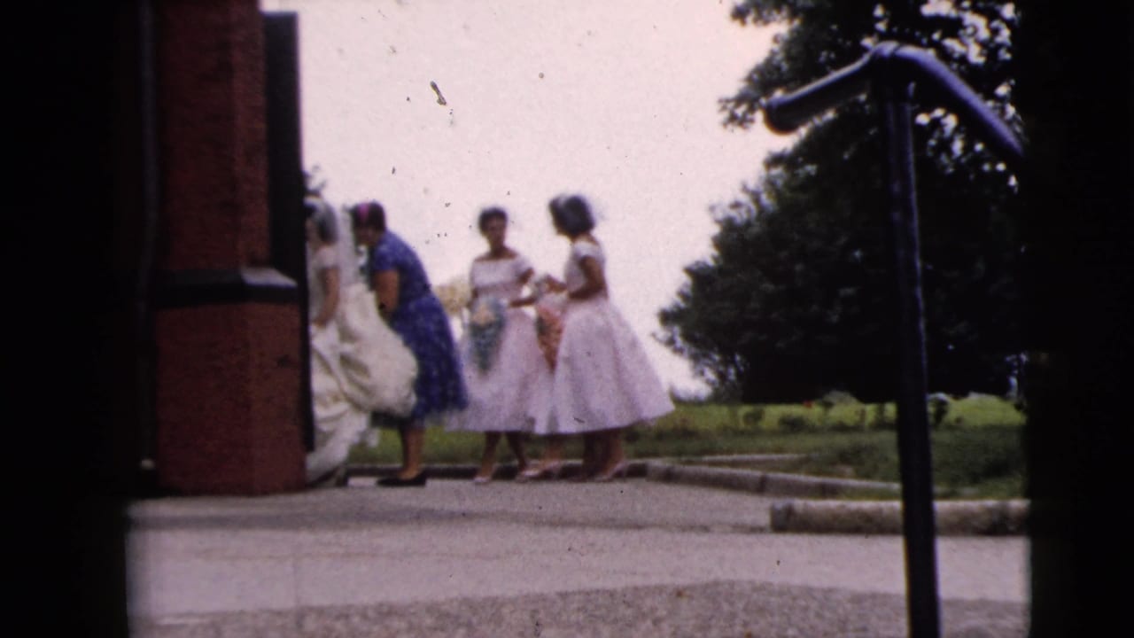 The bridal party remains beside the brick church entrance in Moline, with the bride's white gown partly obscured by the doorway.