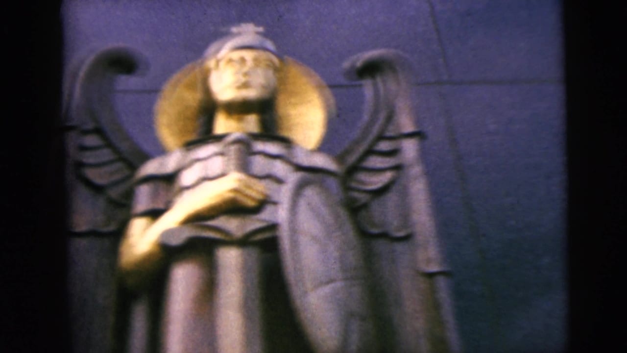 Soft close-up of the angel statue with halo, wings, sword, and shield.