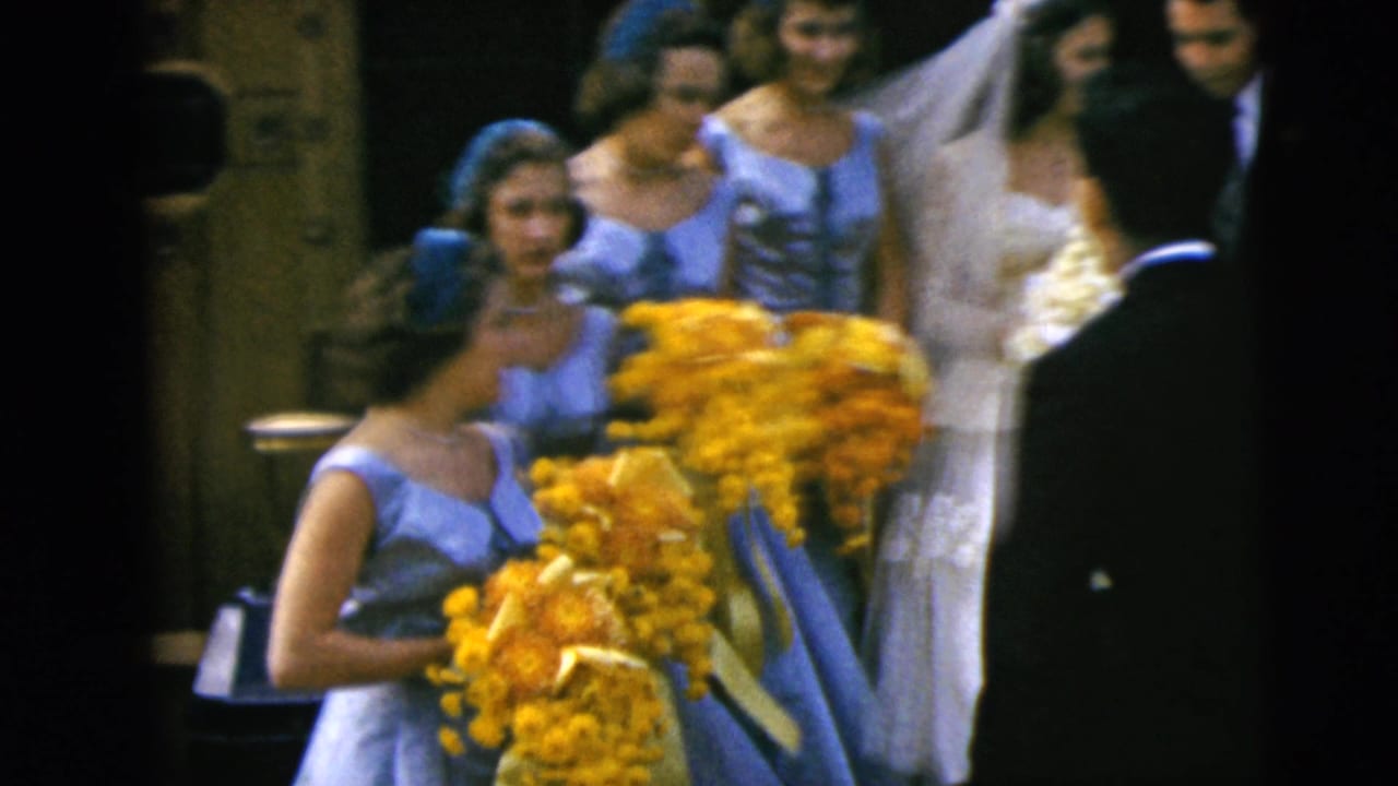 Bride, groom, bridesmaids, and ushers gathered indoors with large yellow bouquets.