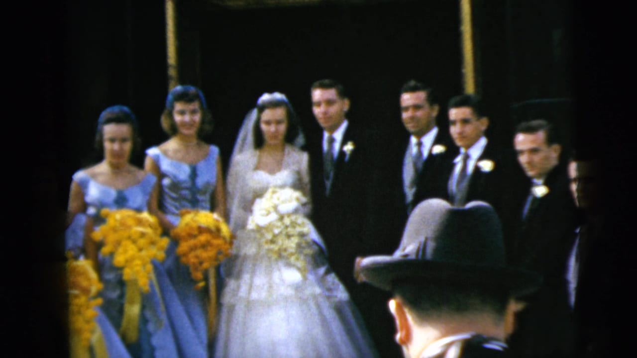 1962 Moline wedding party poses for a photograph, with the bride and groom centered among bridesmaids in blue and groomsmen in dark suits.