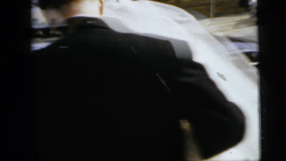 1962 Moline wedding footage showing the bride and groom from behind as they approach a car, with attendants close around them.