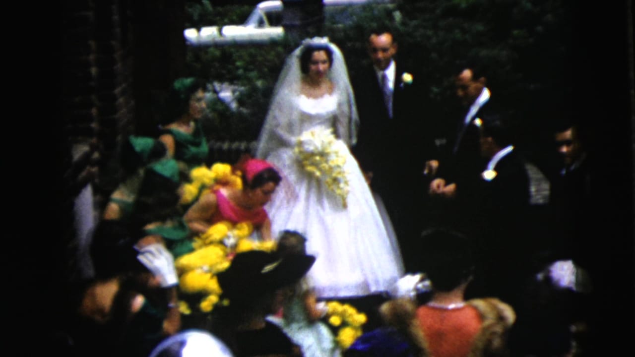 Bride and groom stand near attendants while guests with yellow flowers gather in the foreground.