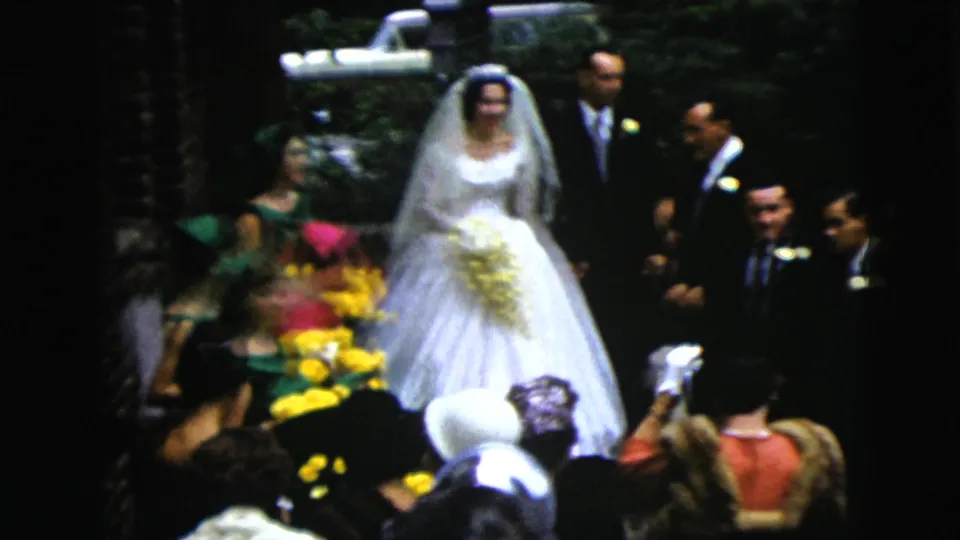 1962 Moline wedding frame with a bride in a white gown and veil carrying a yellow bouquet beside a groom in a dark suit.