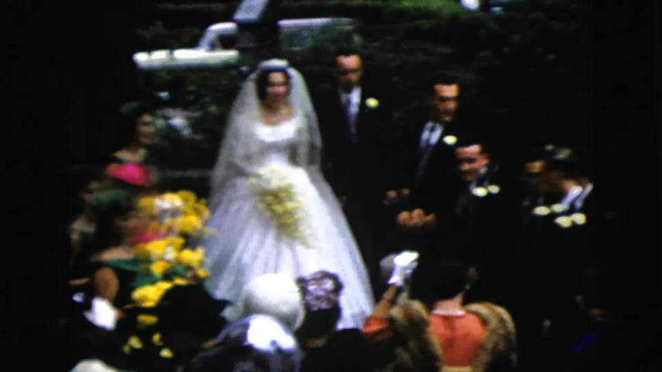 1962 Moline wedding frame showing the bride and groom with attendants and seated guests in a crowded formal ceremony setting.