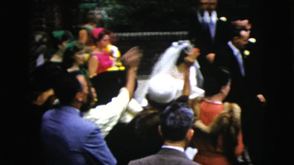 A handheld 8mm view shows the bride turning near the aisle among guests in period clothing during the 1962 Moline wedding.