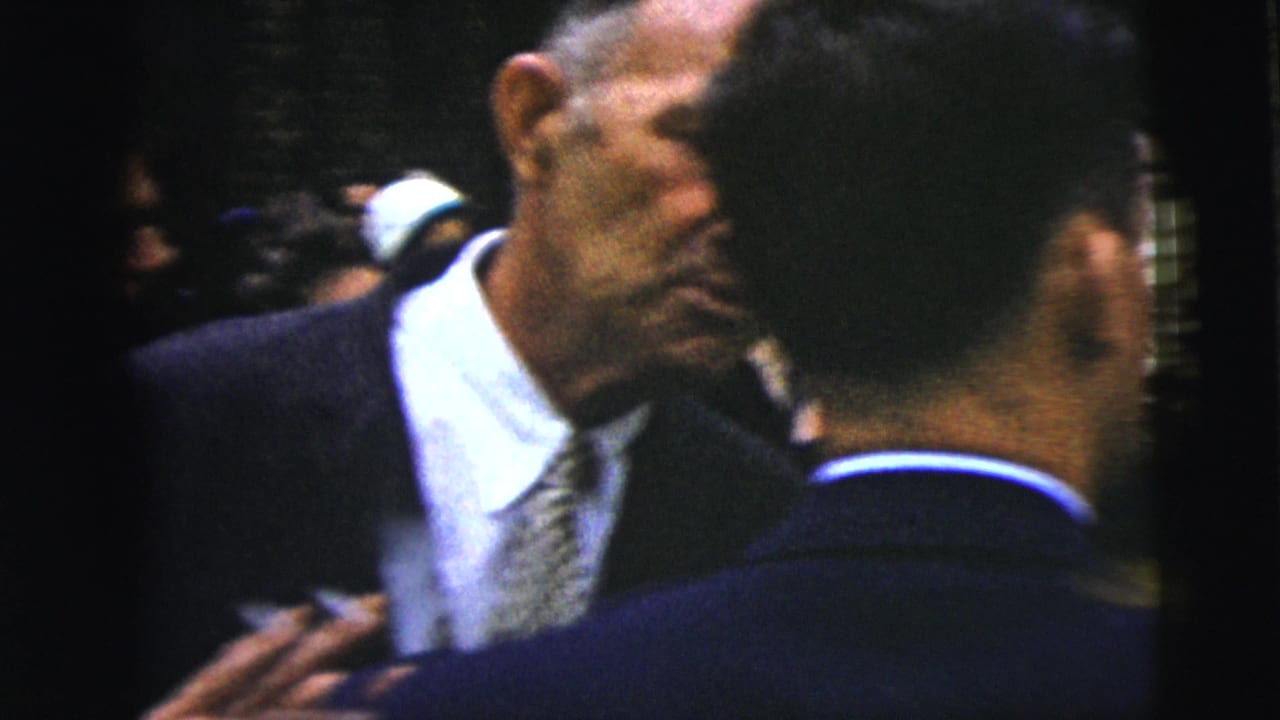 Close crowd view of suited men at a formal outdoor gathering.