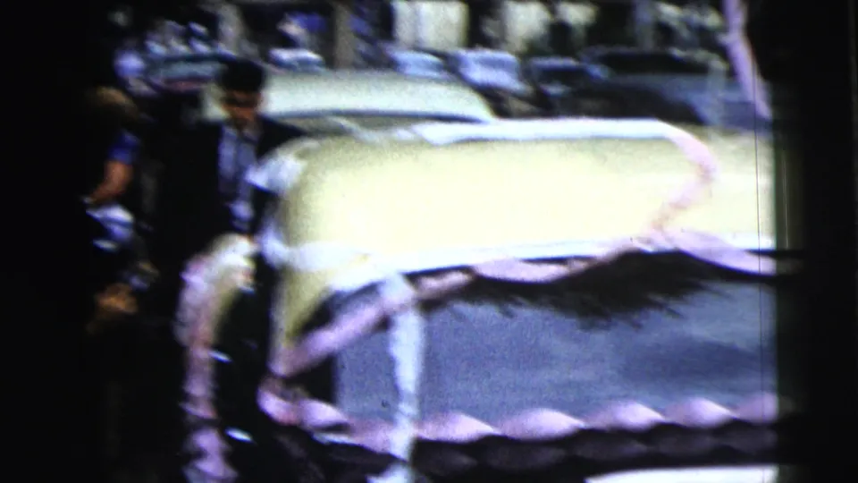 A pale classic car appears beside formally dressed guests in the 1962 Moline outdoor church-event footage.